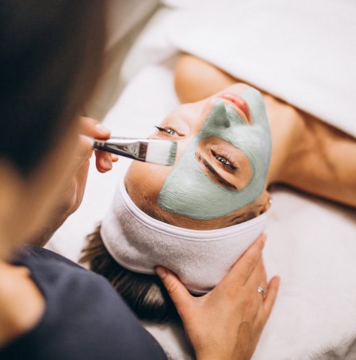 Cosmetologist applying mask on a face of client in a beauty salon