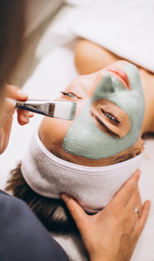 Cosmetologist applying mask on a face of client in a beauty salon